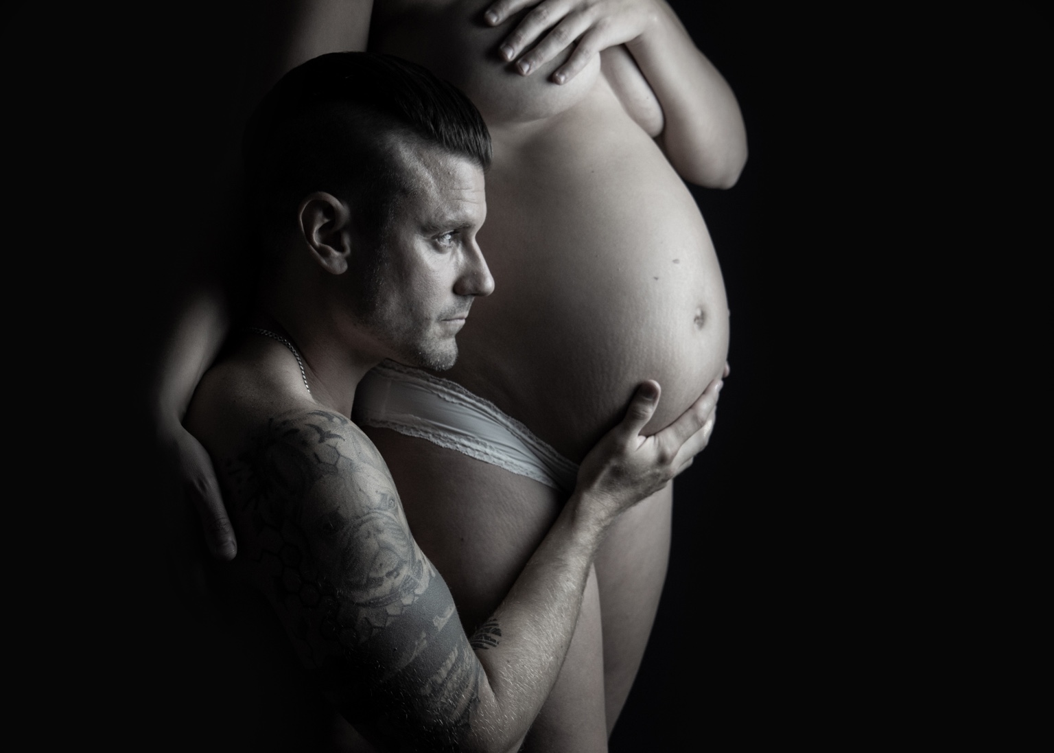 Man håller om en gravid mage i svartvitt