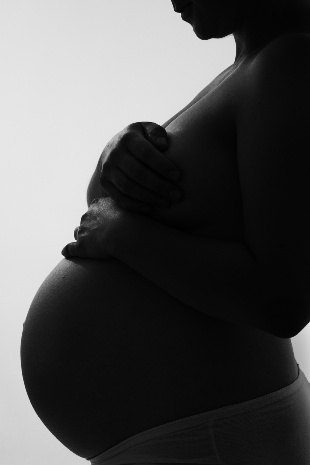 Gravid mage och händer i svartvit silhuett